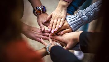Seven overlapping hands, indicating community.