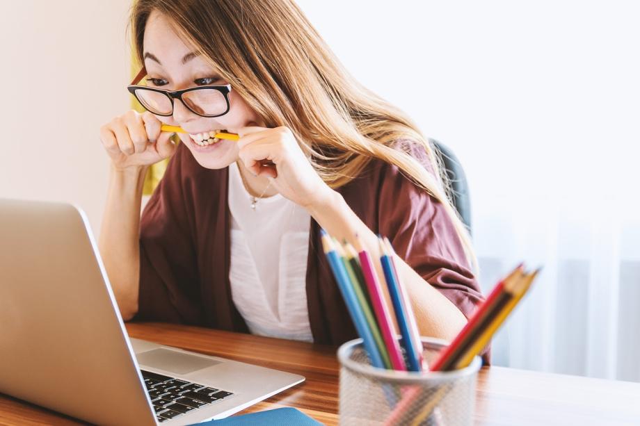 Lady in front of her computer, biting her pencil.